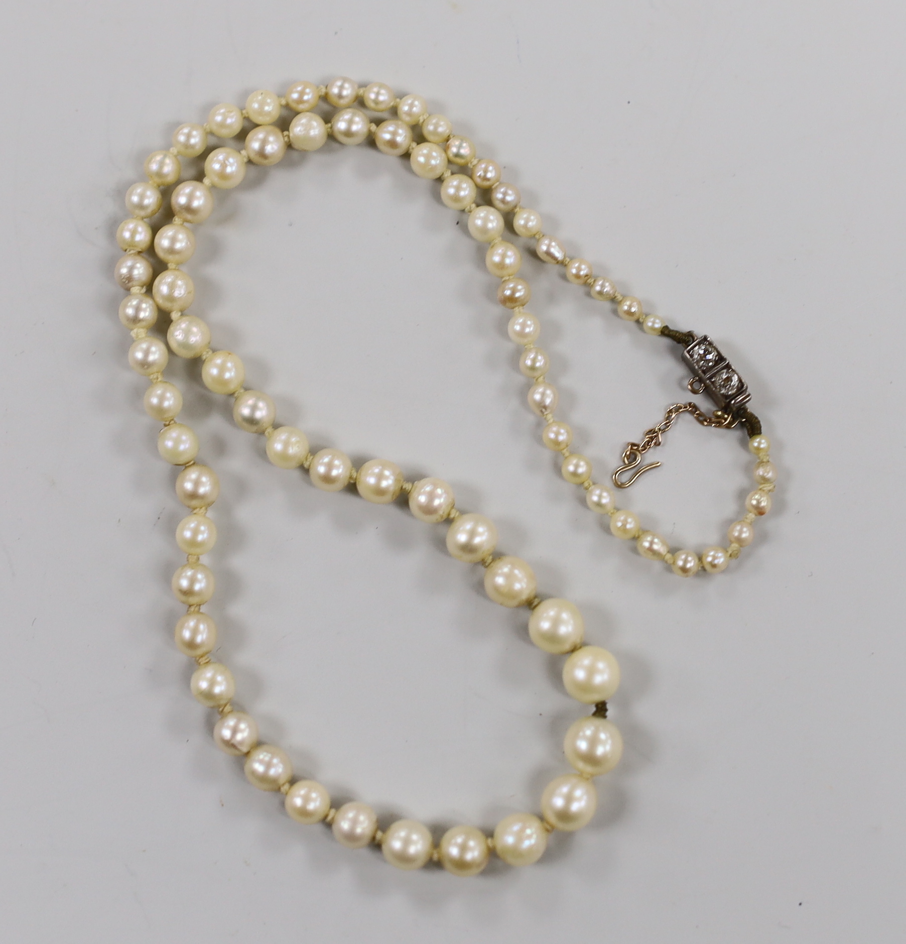 A single strand graduated cultured pearl necklace, with two stone diamond set yellow metal clasp, 37cm.